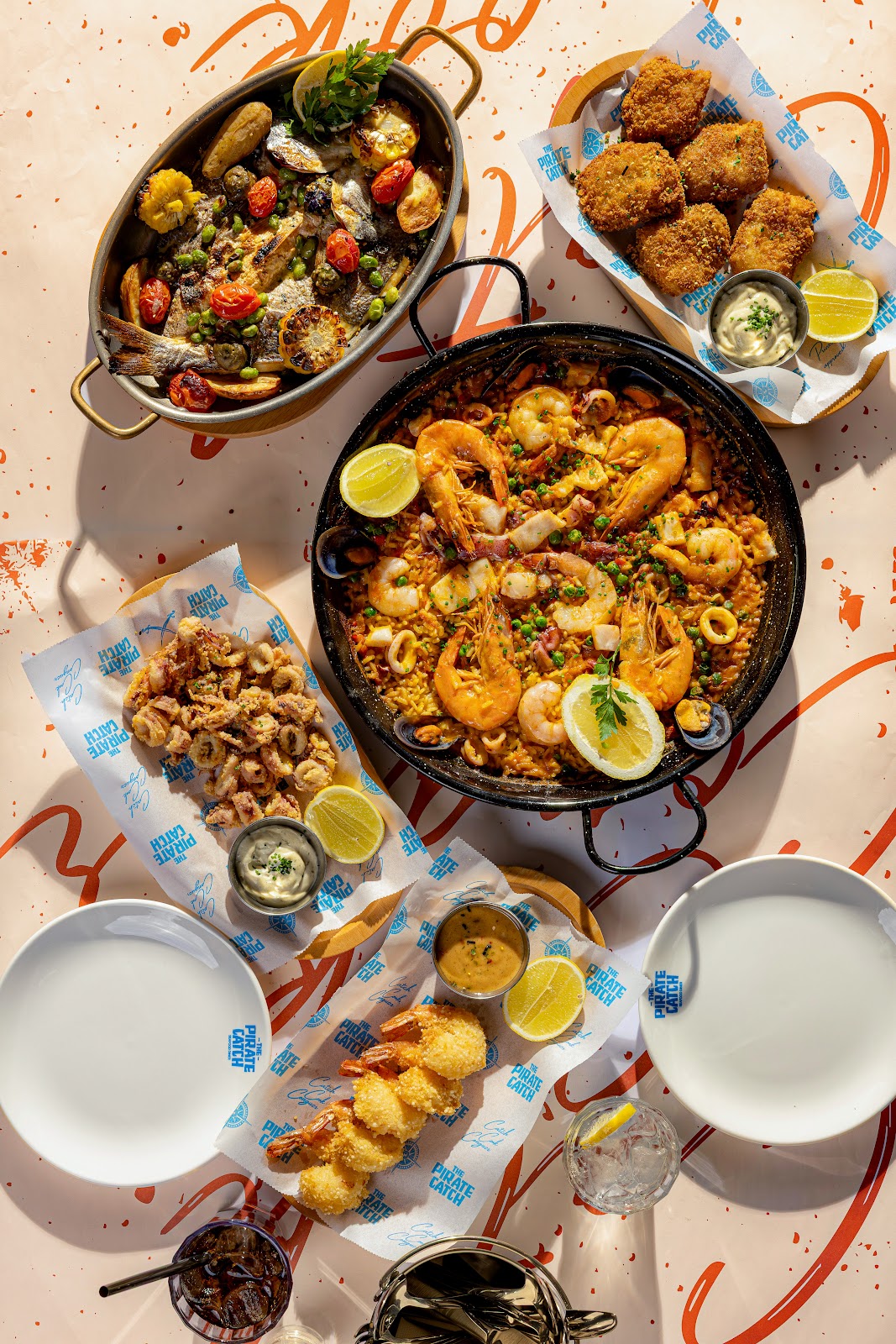 A seafood paella pan and fried platter photographed from above on Pirate Catch paper