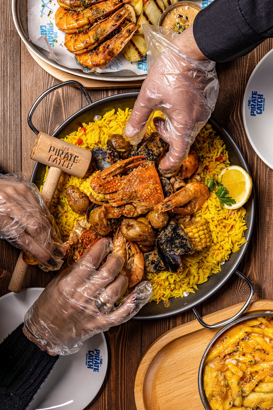 Gloved hands digging into a seafood boil over yellow rice