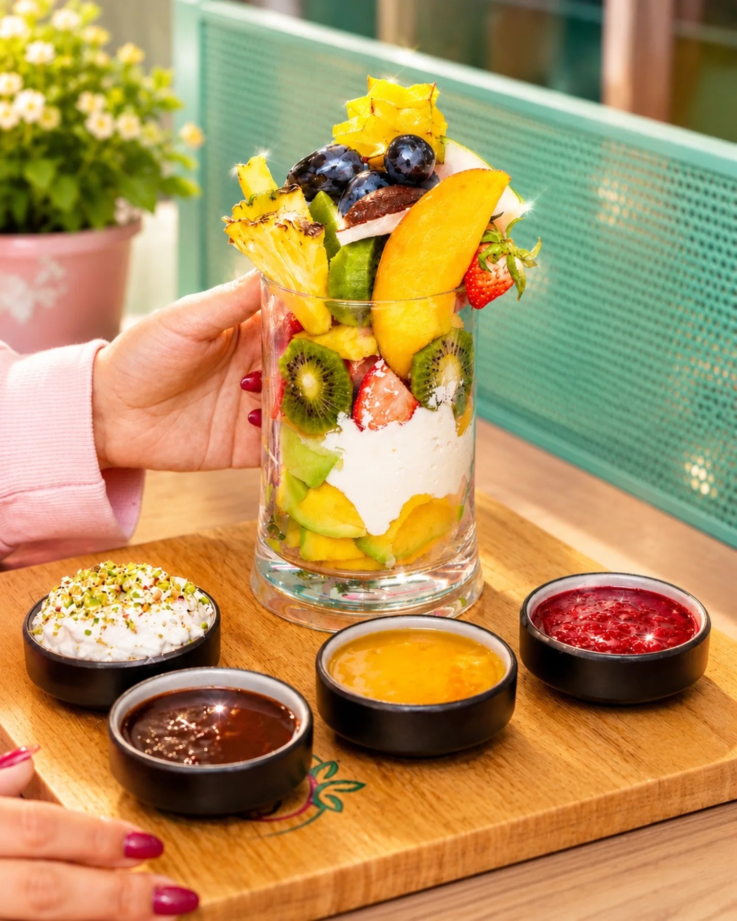 A Ramadan Juice fruit cup on a wooden board with cream and fruit sauces