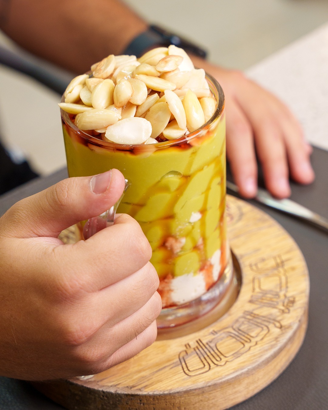 A mango cocktail topped with nuts, handed across the counter