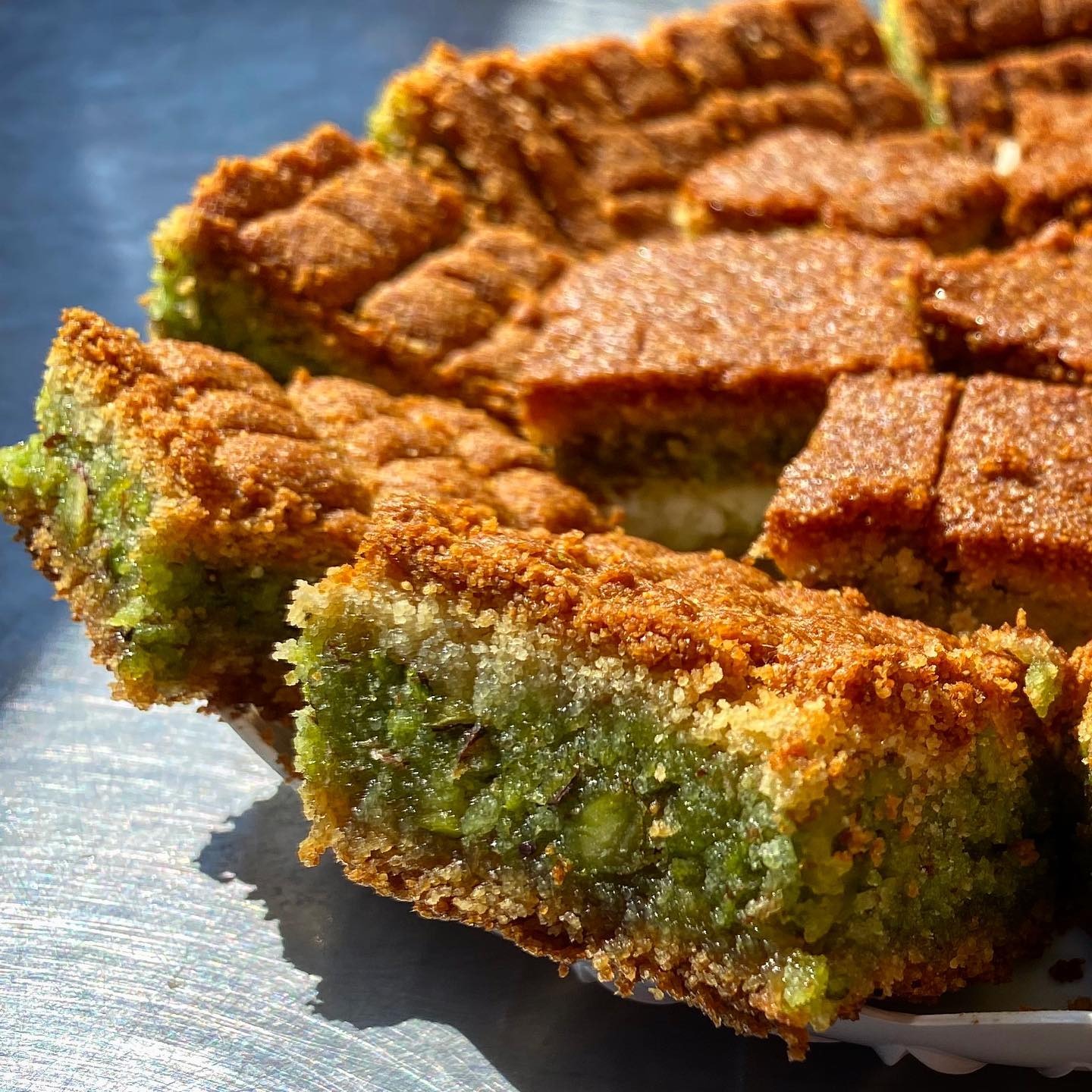 Sfouf cut close, a green pistachio seam running through the slice
