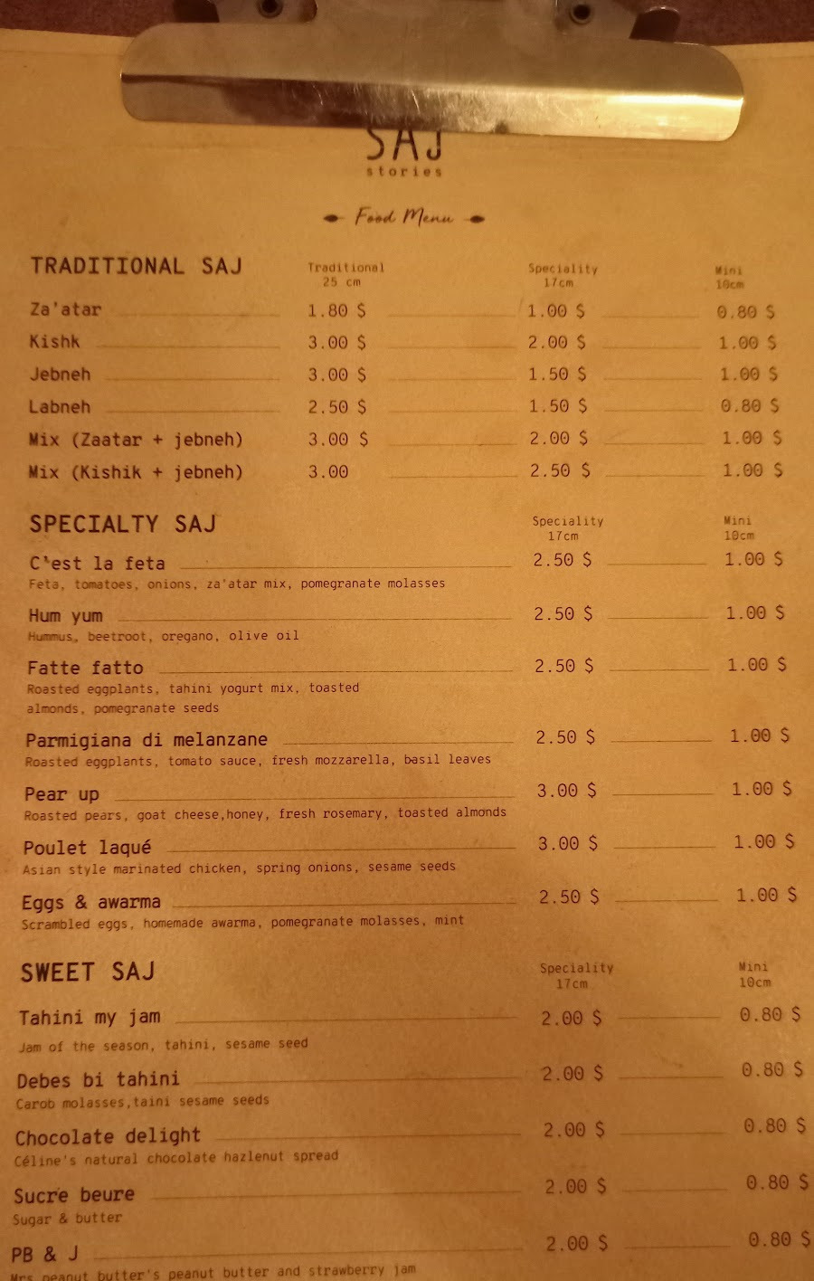 The printed Saj Stories food menu on its clipboard