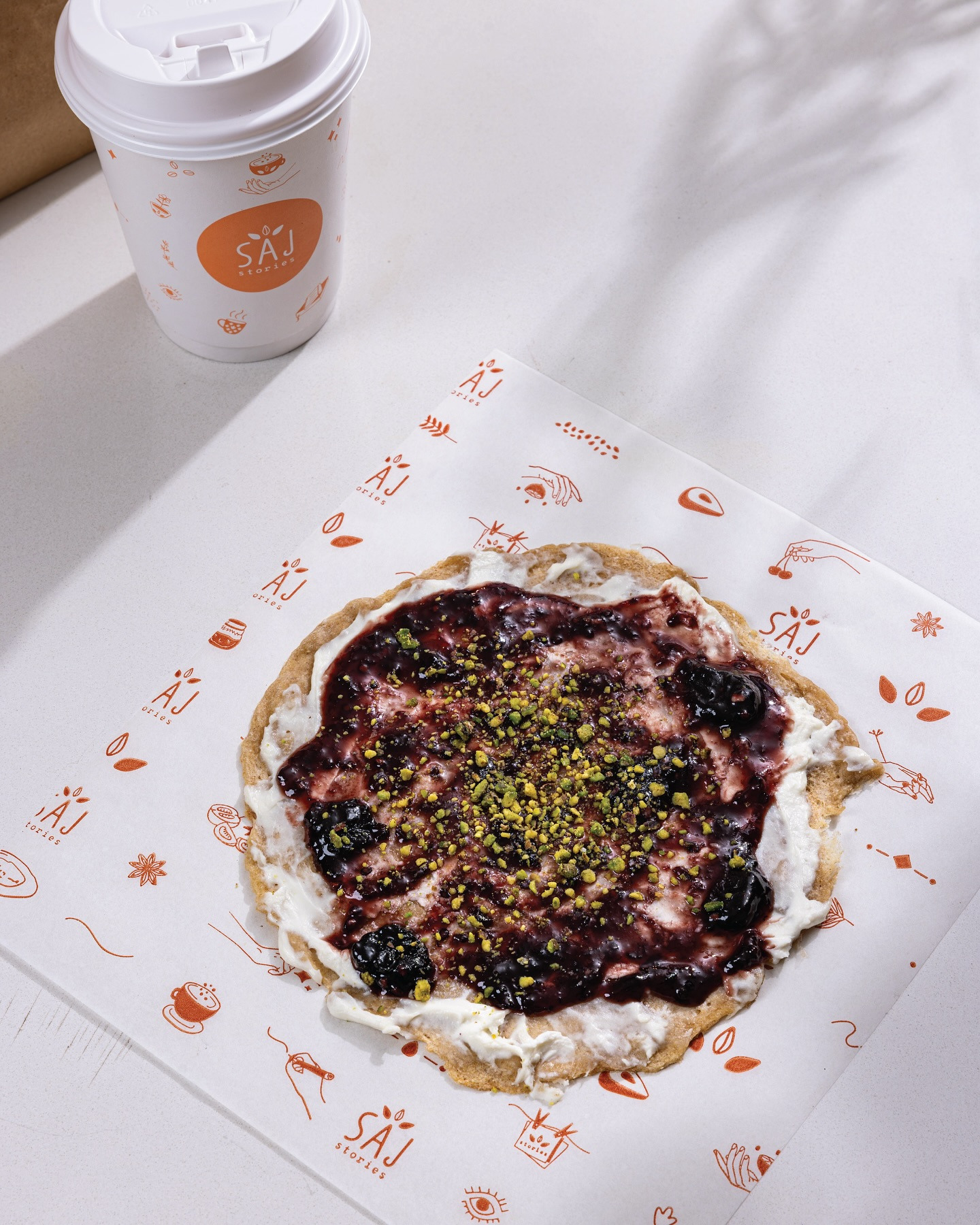 A sweet saj with a dark jam and pistachio over a cream base