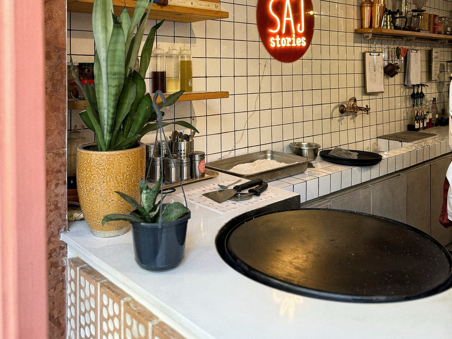 The counter with the black saj dome, the neon roundel and the tiled wall
