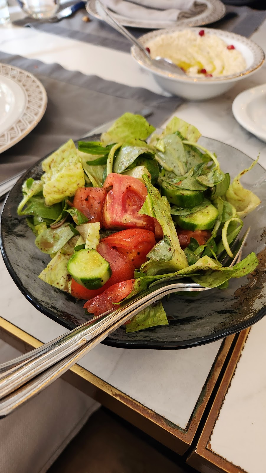 A glass bowl of cut salad held over the table