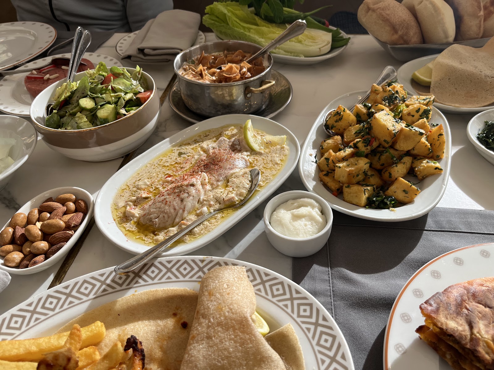 A family table with a whole cooked fish, potatoes and mezze