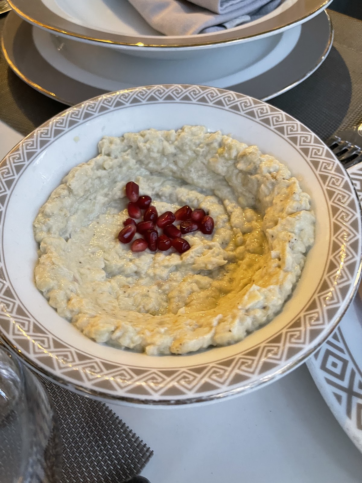 Moutabbal crowned with pomegranate seeds on a patterned plate