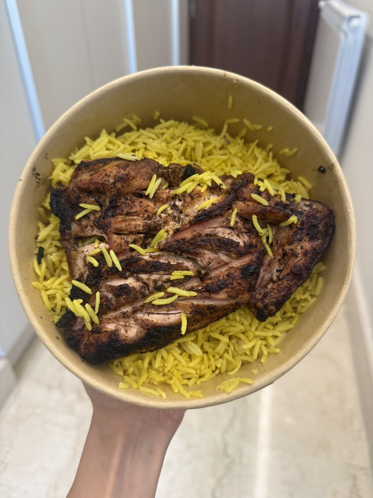 Charcoal chicken served over yellow rice in a bowl