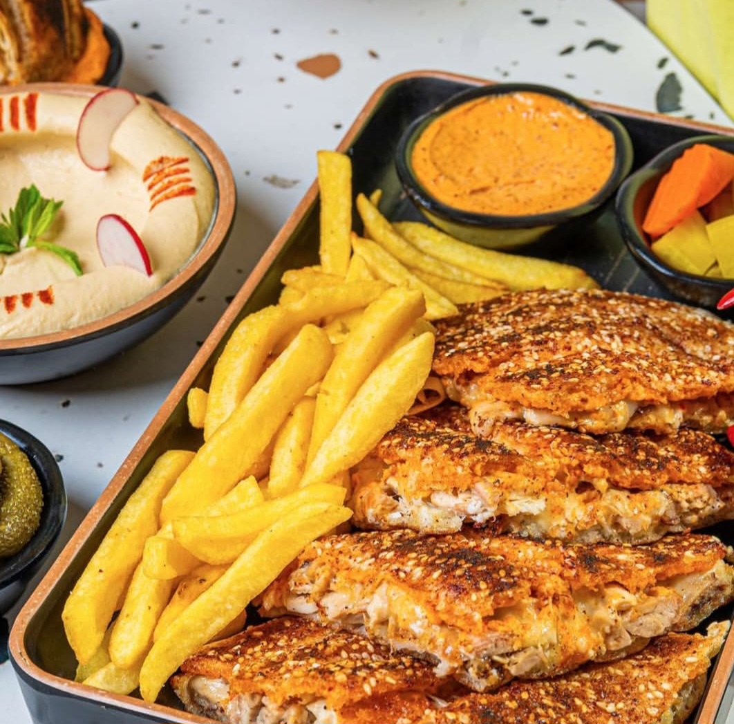 A tray of Al Shayeb grilled chicken with fries, hummus, muhammara and pickles
