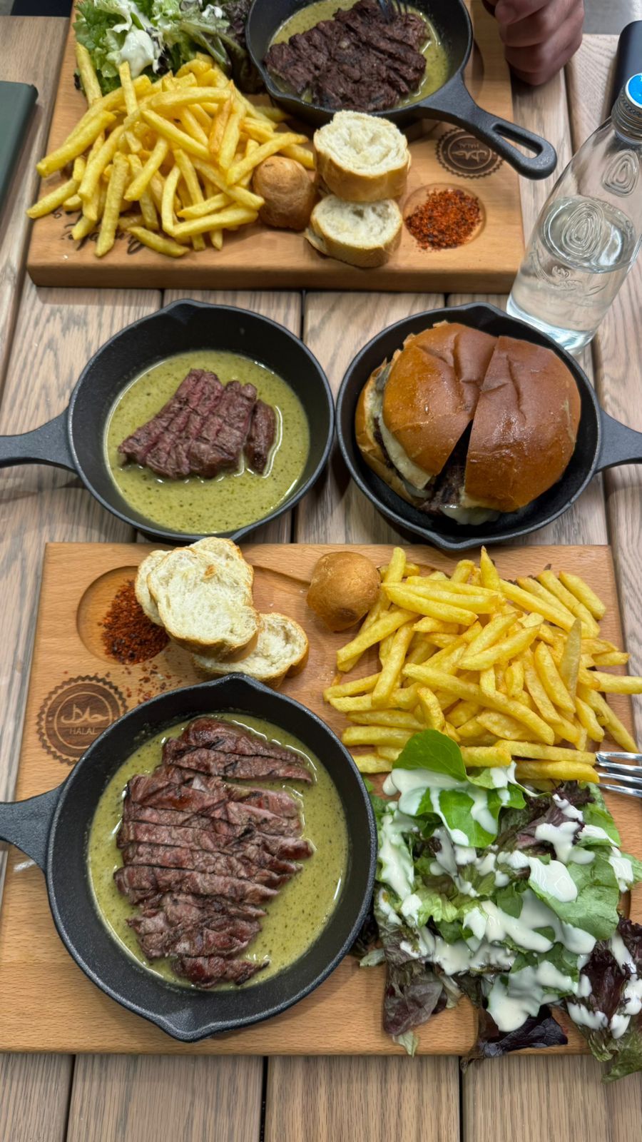 Two wooden boards with steak skillet, burger and fries