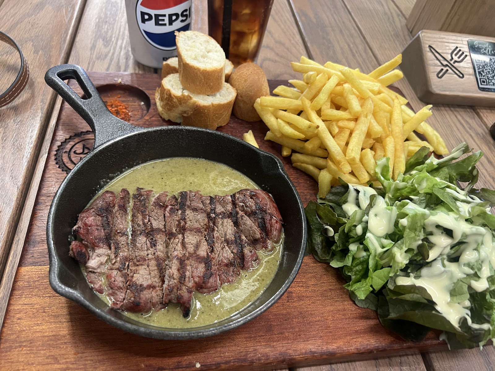 Grilled beef steak in a skillet of butter sauce with fries and salad