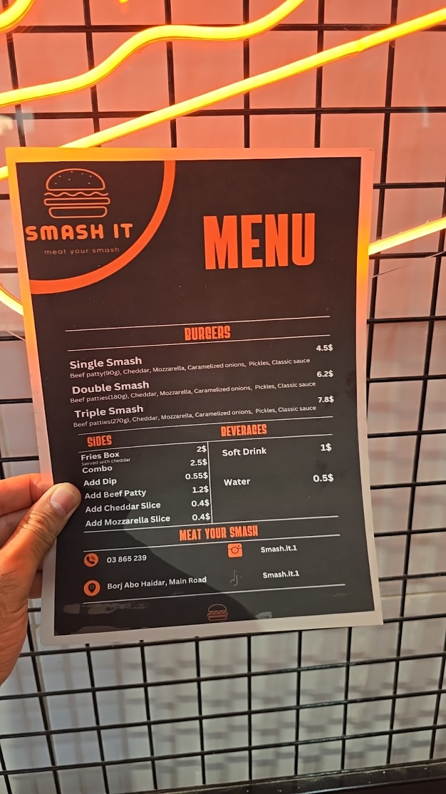 The printed Smash It menu card held up at the counter