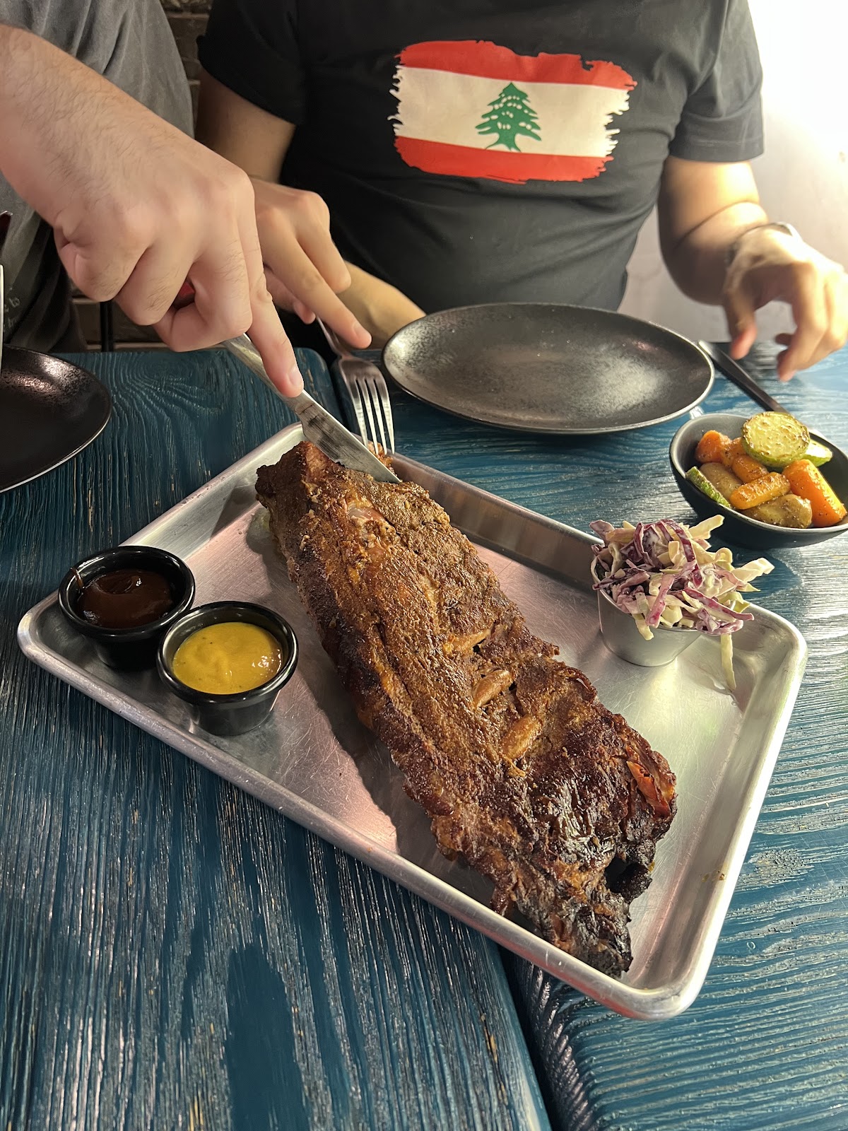 Ribs on a steel tray being cut at the table