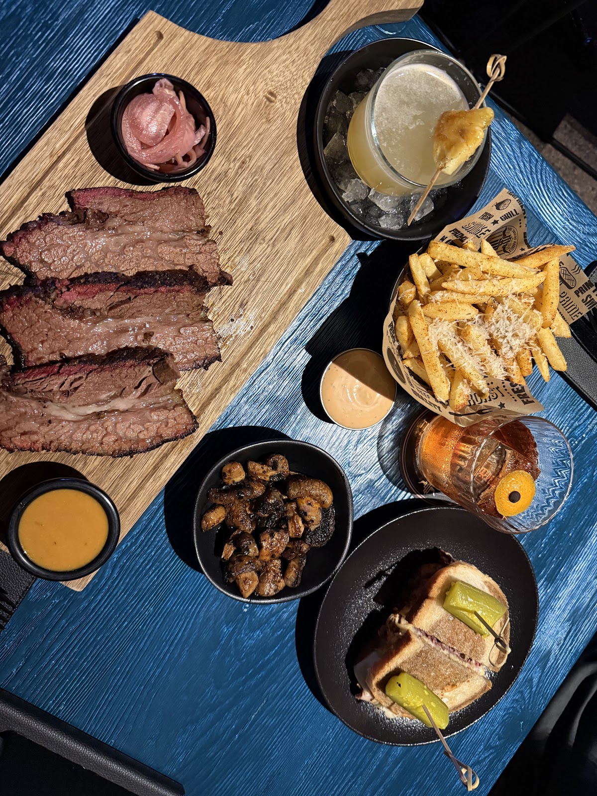 A brisket board with fries, sides and cocktails from above