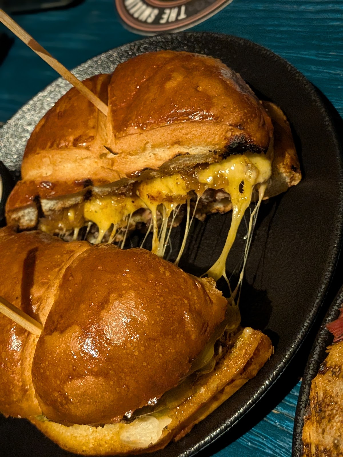 A smash burger with melted cheese pulling on a skillet