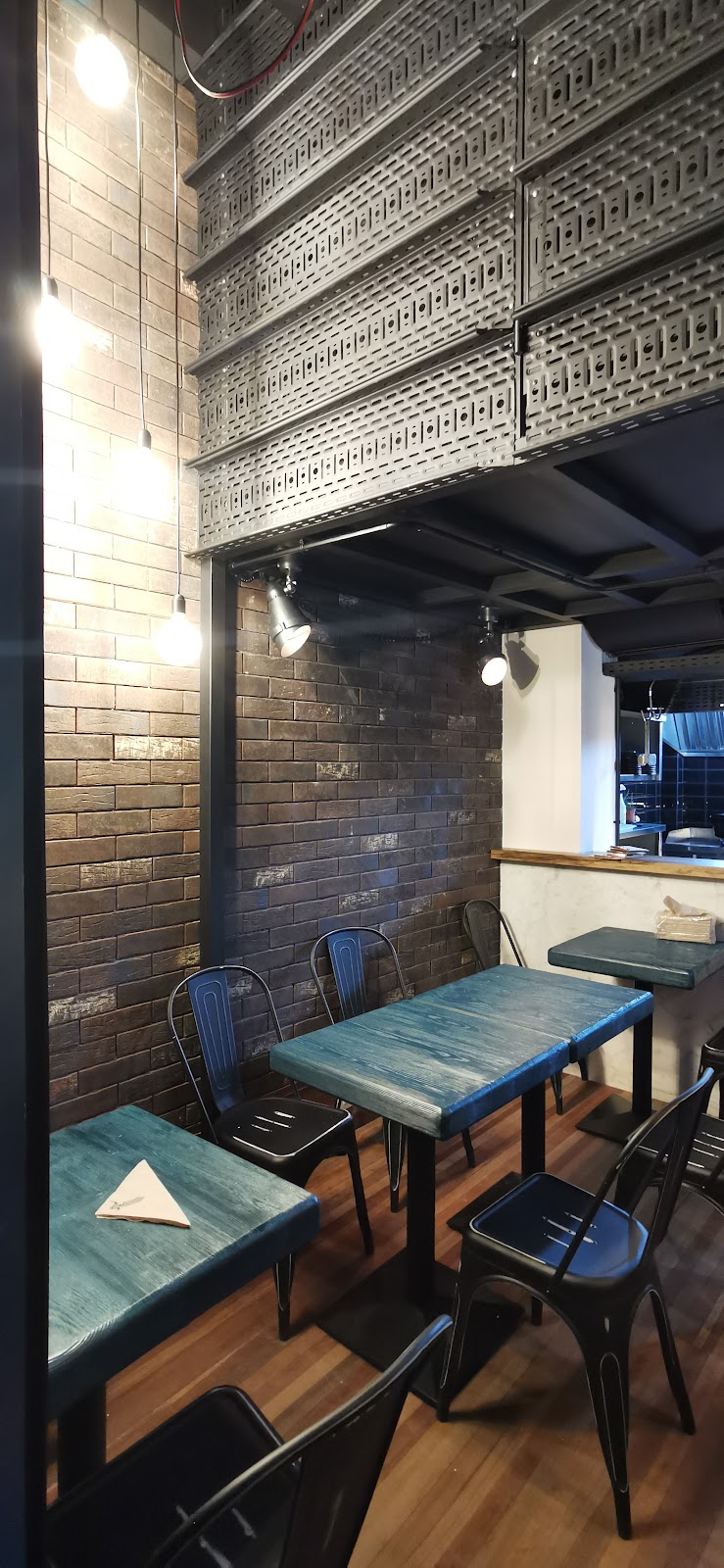 The corner of the room with blue tables, black chairs and glass bricks