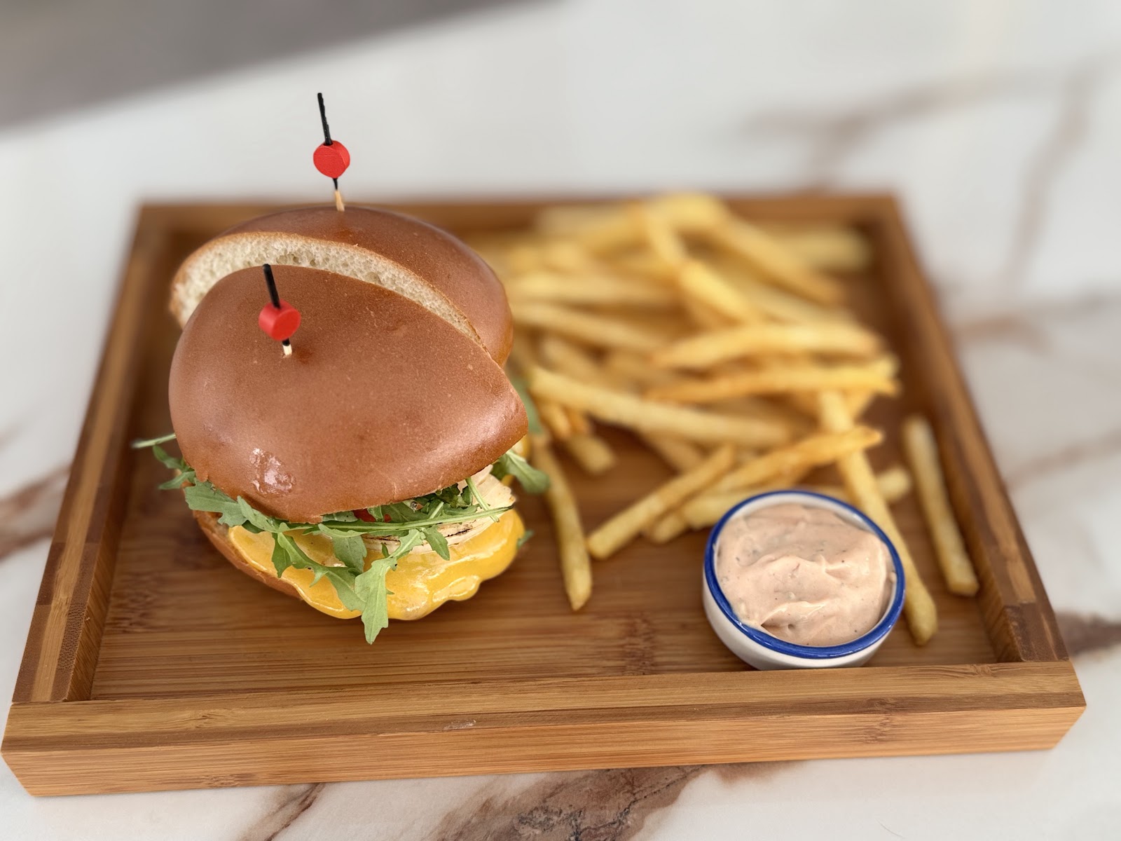 A burger with a pick and fries on a wooden board at Soul Beirut