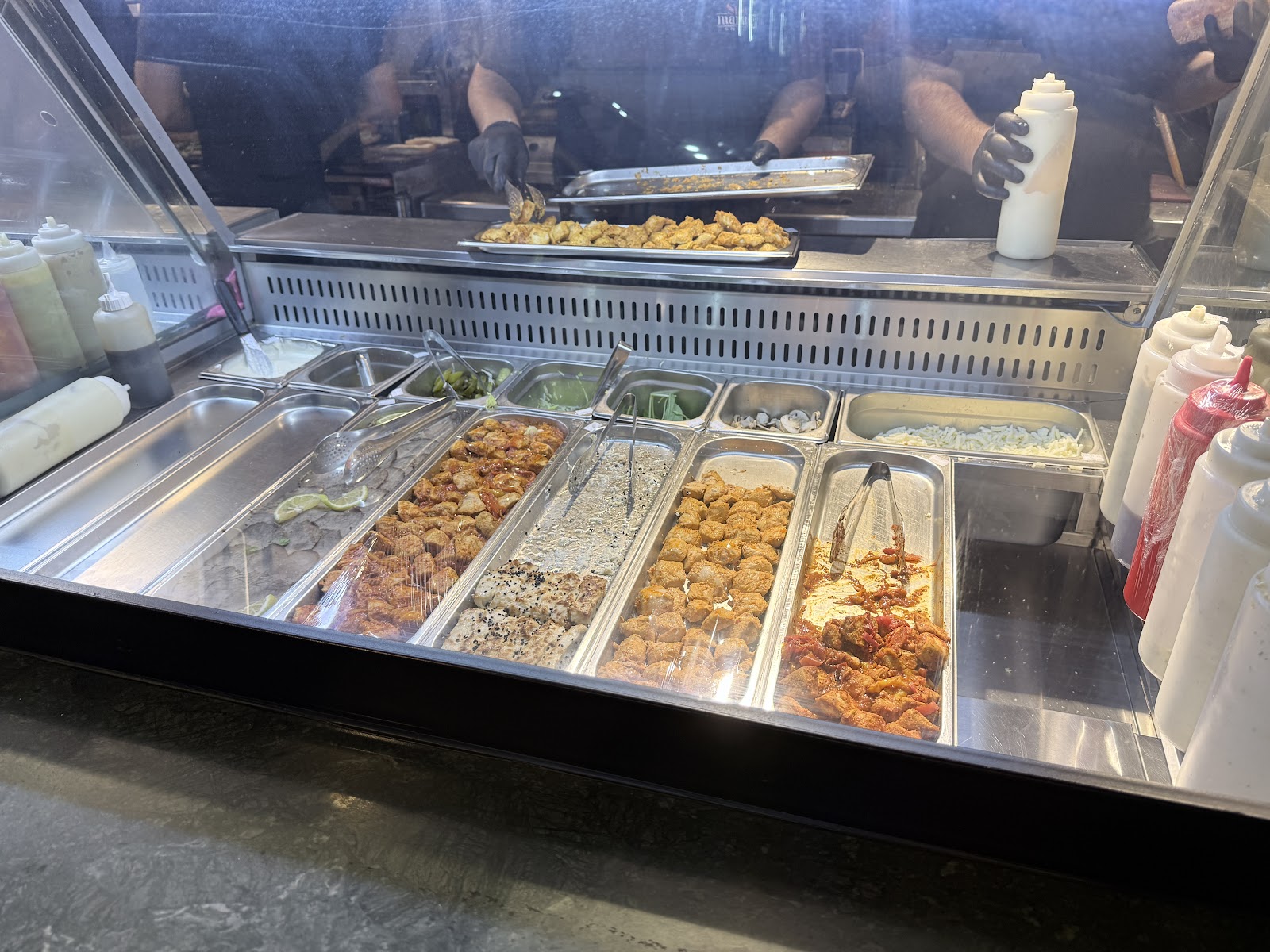 The chilled line of vegetables and toppings behind the glass