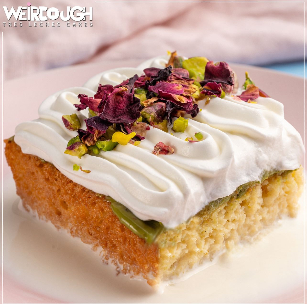 A slice topped with cream, pistachio and rose petals