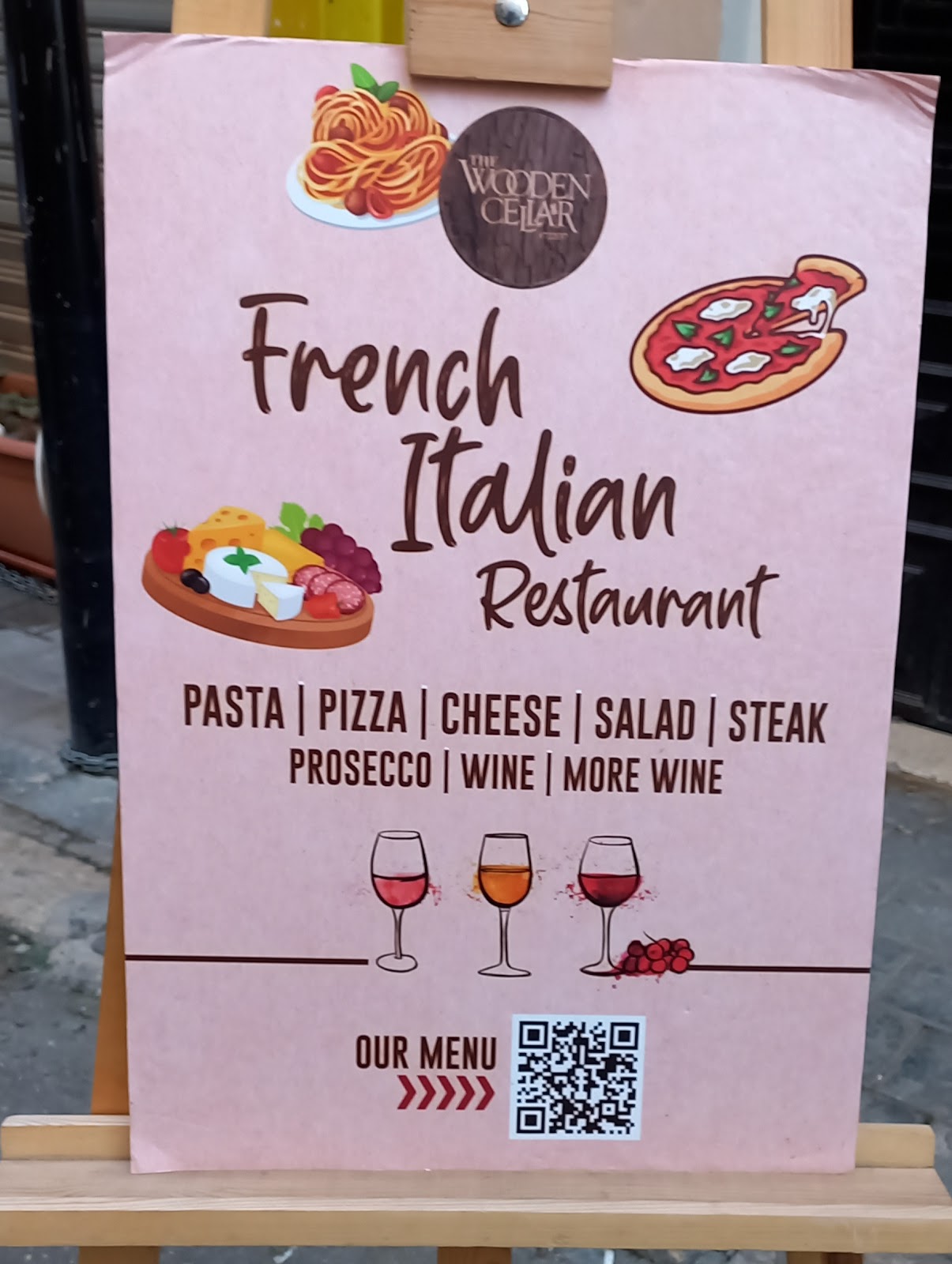 The pink French Italian Restaurant easel sign on the pavement