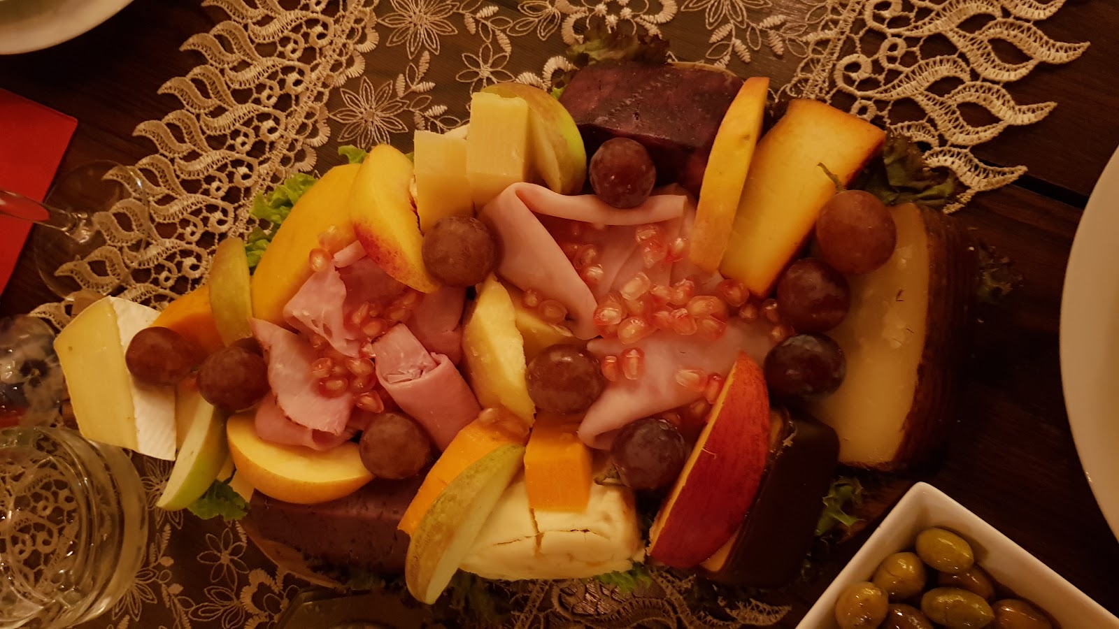 A charcuterie and cheese board with fruit, served at the table