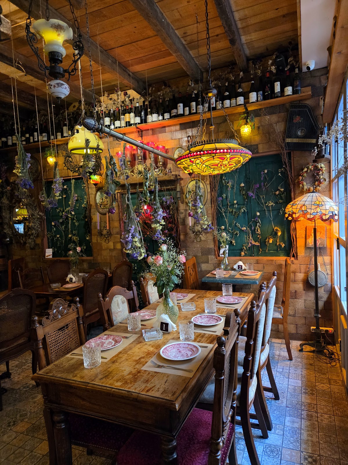 The Wooden Cellar dining room: wooden tables set under stained-glass lamps, wine shelves behind