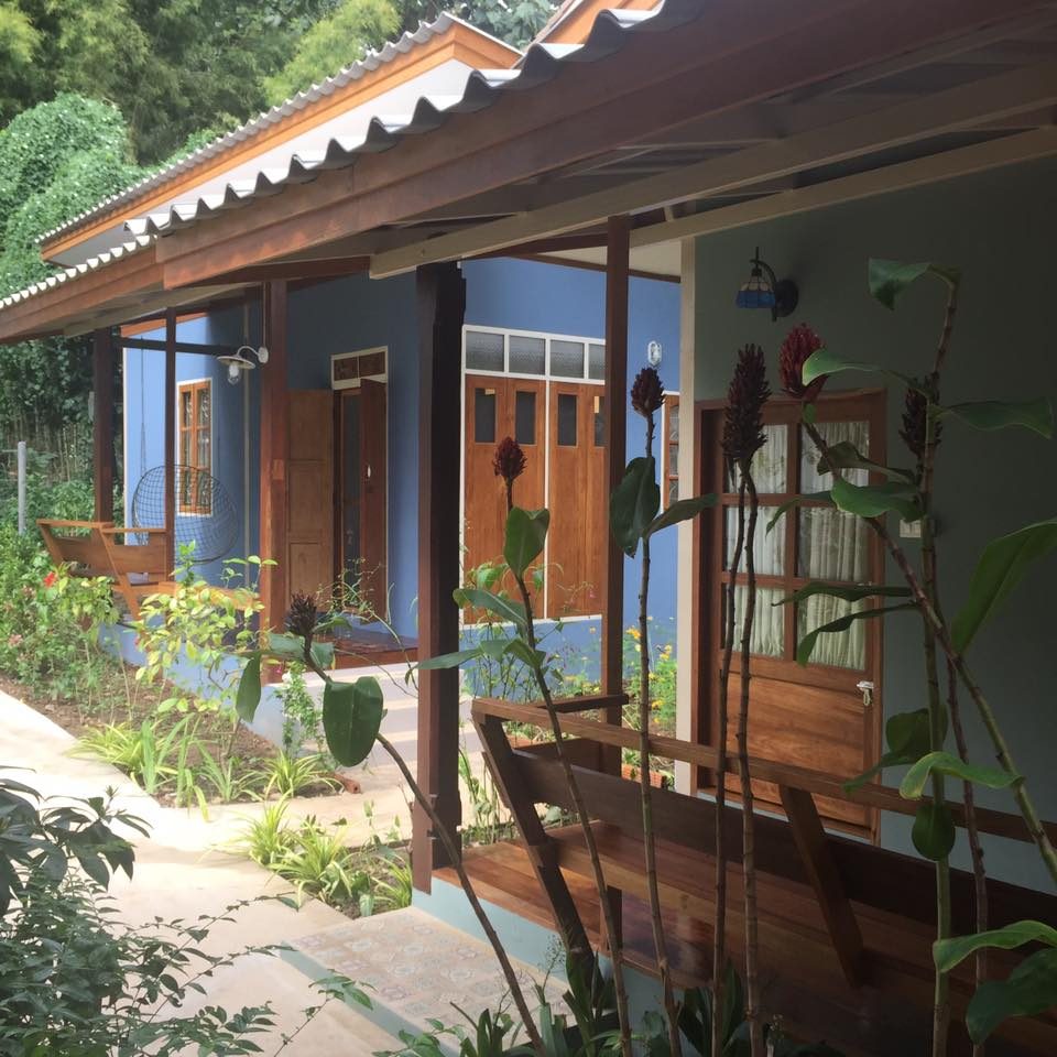 Teak bungalow with blue window frames and a leafy garden at Pai Yan Noi