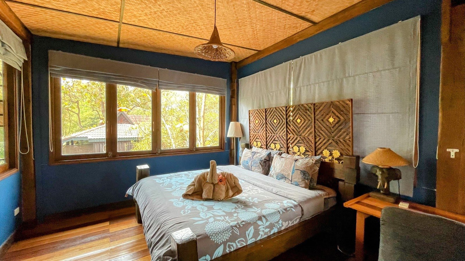Blue-walled teak room with a carved headboard