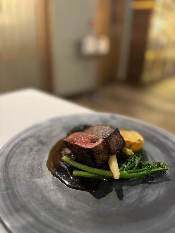 Beef carved over a dark jus with charred greens