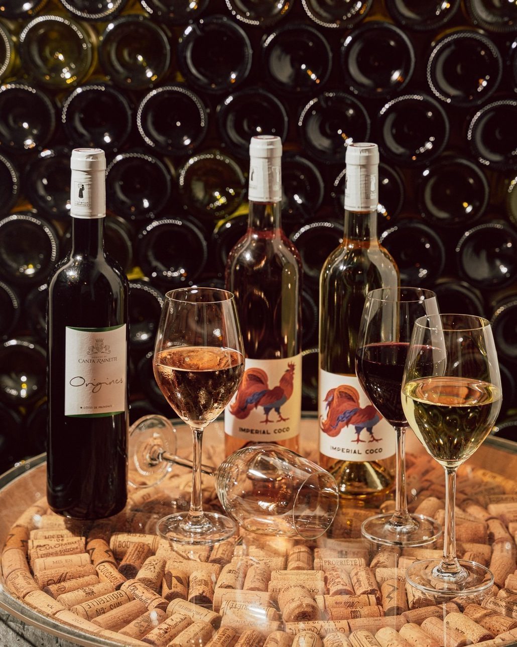 Bottles and two poured glasses on a cork tray in front of the CORKS bottle wall