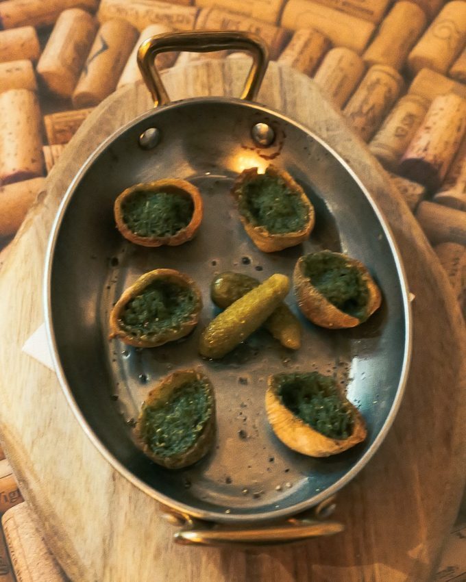 Escargots baked in garlic butter, served in a small pan at CORKS