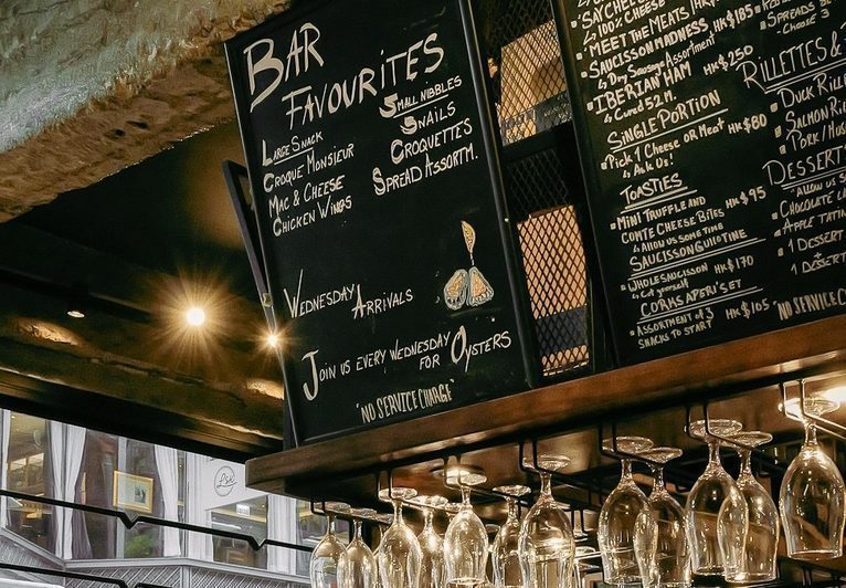 The CORKS bar favourites chalkboard, hand chalked above the hanging glasses