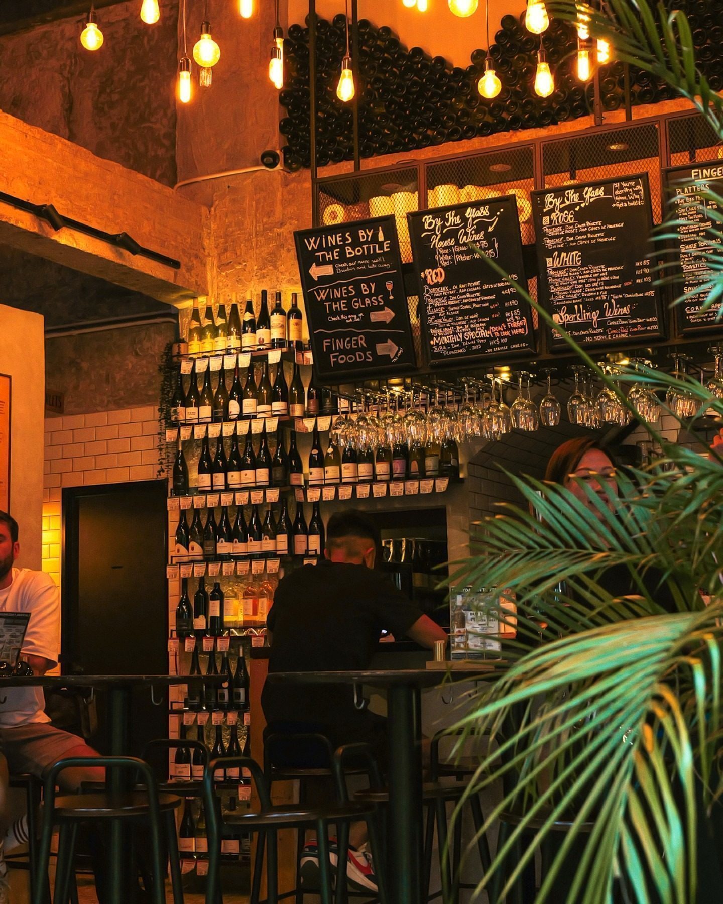 Inside CORKS: the wine wall, the hanging bulbs and the chalkboards over the bar