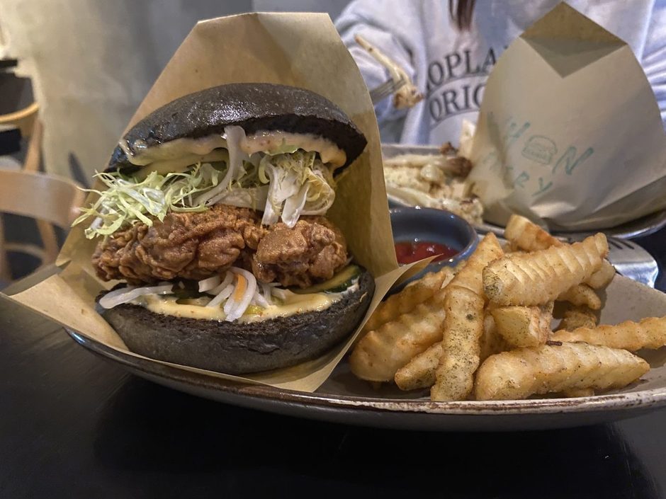 The charcoal bun burger with crinkle fries and ketchup on a stoneware plate