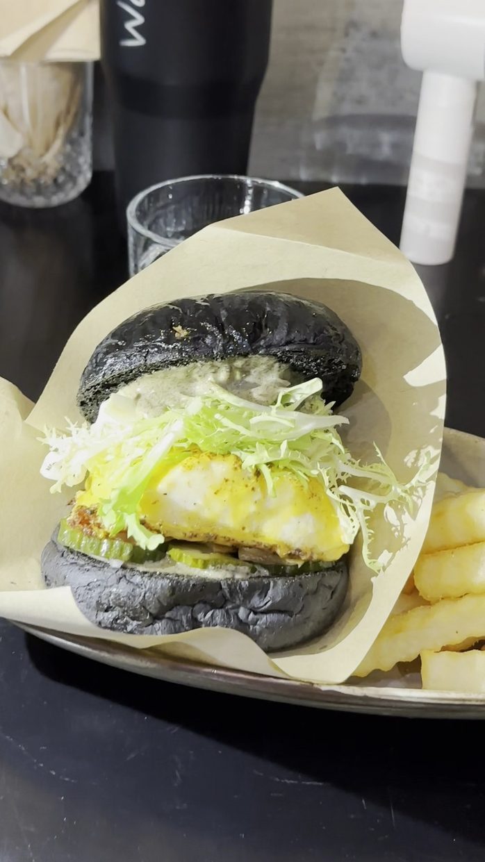 Grilled halibut in a charcoal bun with frisee