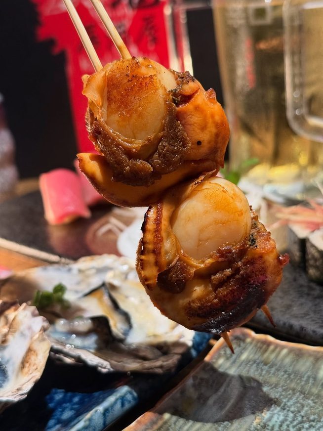 A grilled scallop in its shell at Kuki Izakaya