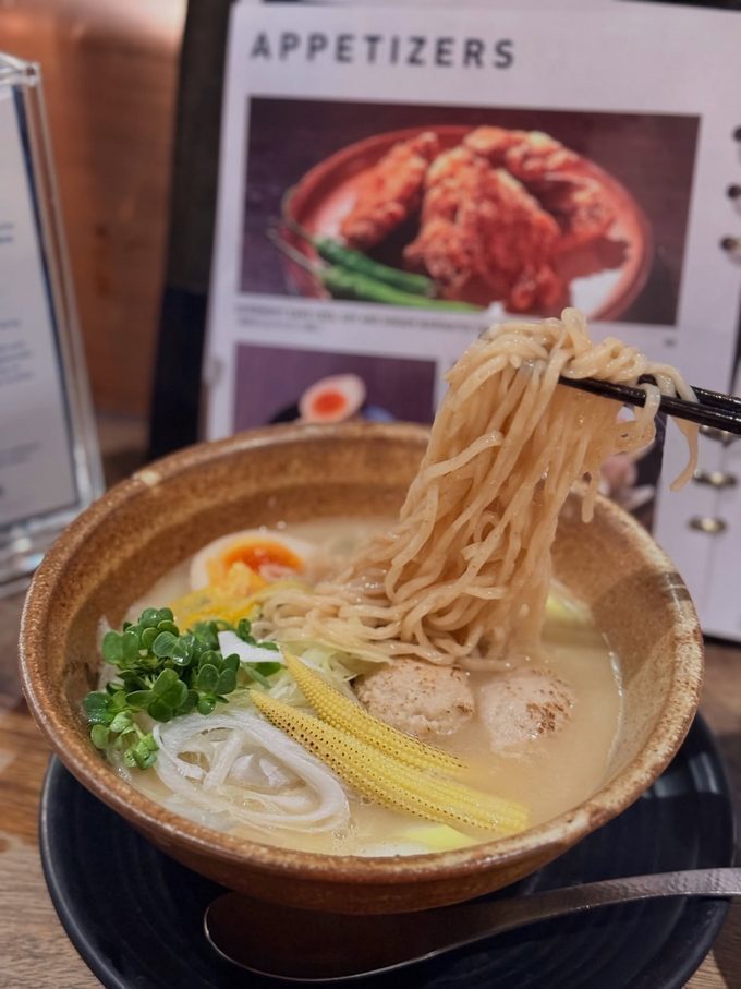 Noodles lifted from a bowl of eight-hour chicken broth ramen at NOJO