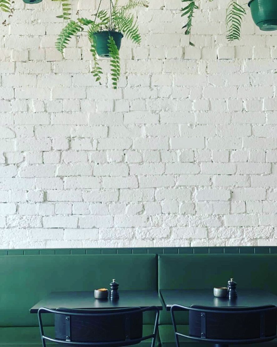 Inside Blonde: white brick, the green banquette and the counter