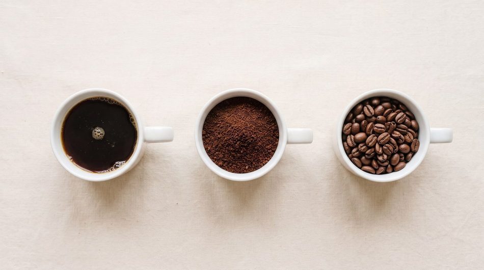 Still life: brewed coffee, ground coffee and whole beans in three cups