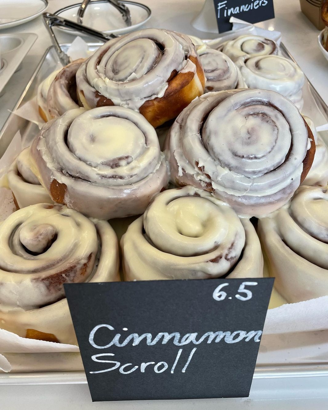A tray of glazed cinnamon scrolls with their chalk price tag at Heart Coffee